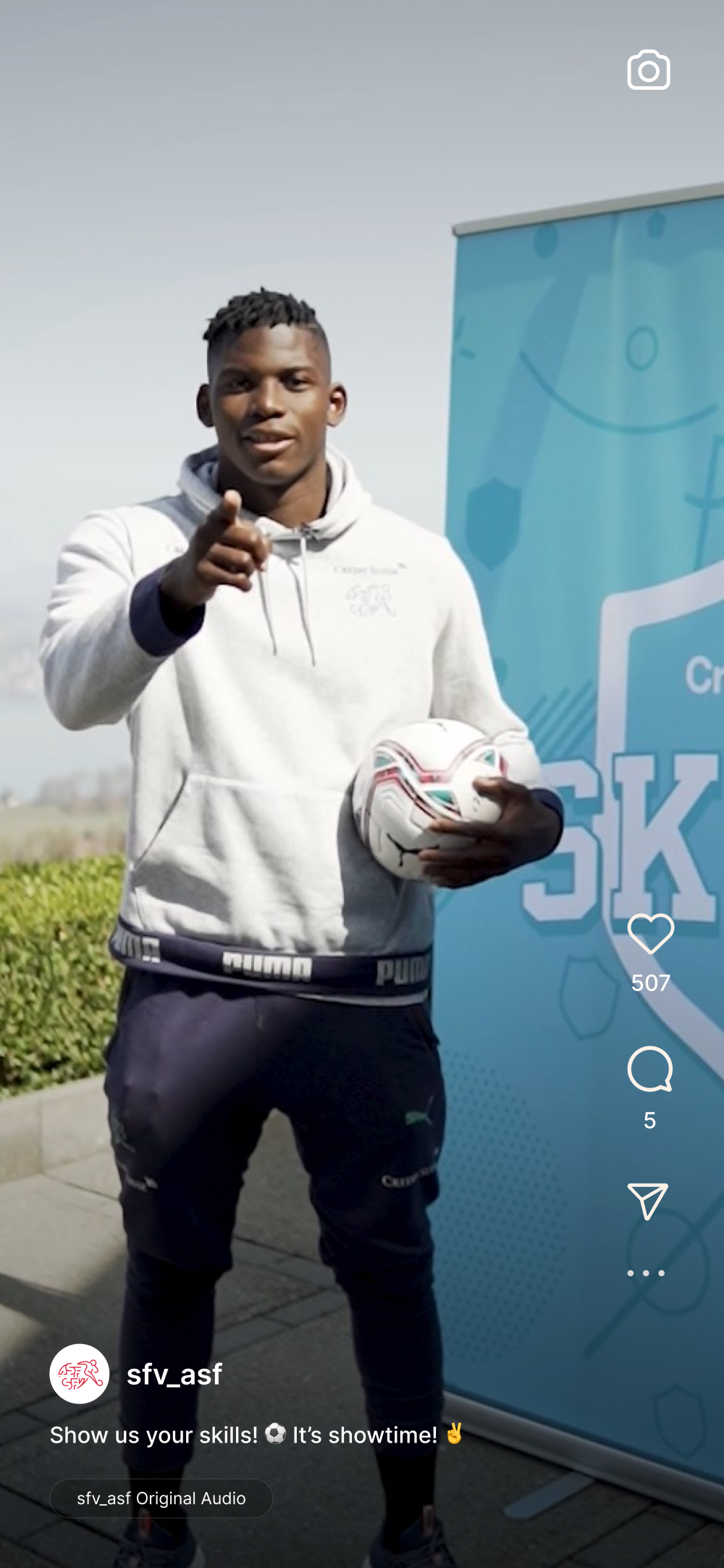 Breel Donald Embolo steht vor einer Credit Suisse Skills Wand mit einem Ball in der Hand.